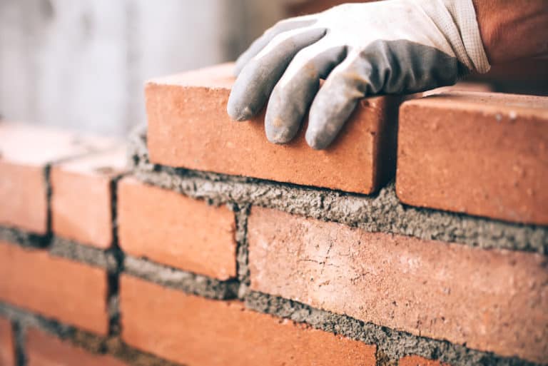 hand laying bricks on a wall