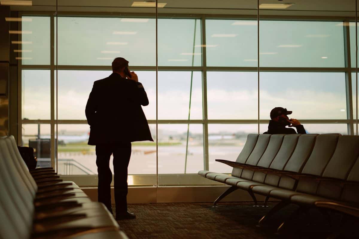 standing businessman talking on iphone in airport terminal