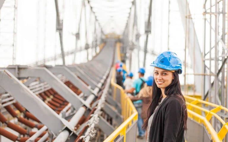 women in construction helmet smiling at camera at construction bridge site