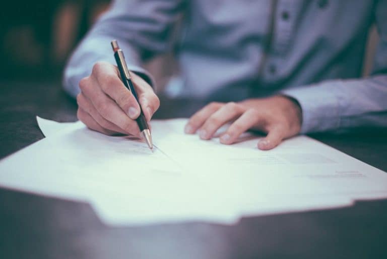 close up of a business man writing on a piece of paper at his desk