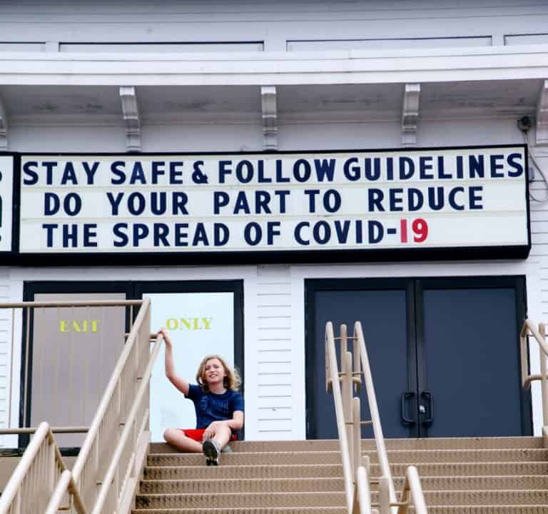 young boy sitting on a staircase in front of a COVID-19 sign