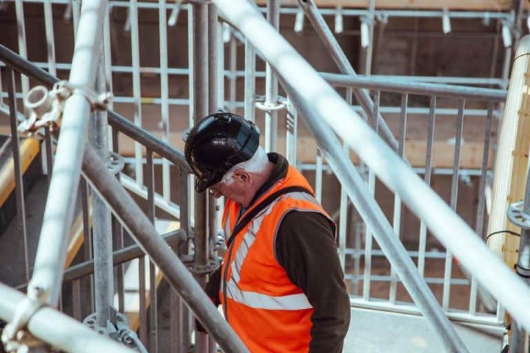 construction man in high vis vest walking up a staircase