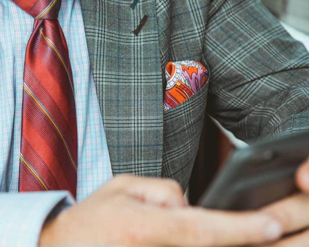 close up of business man on his phone with colorful handkerchief in jacket front pocket