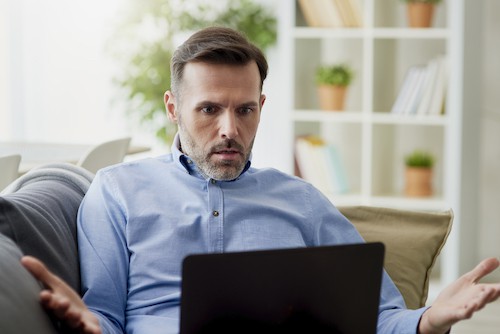 man looking confused and angry working home on a computer