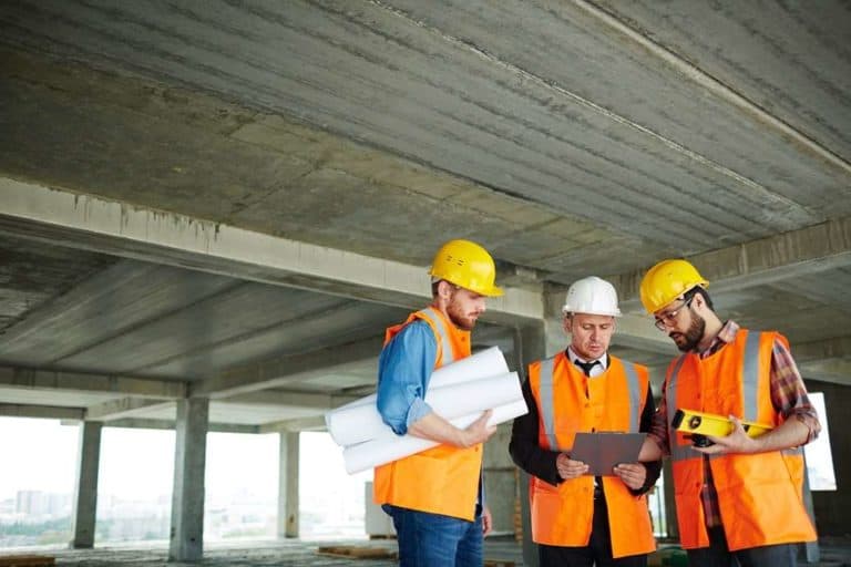 group of three construction workers looking at clipboard