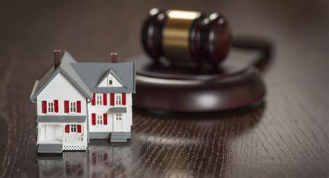 A model of a house and a gavel on a table illustrating an anticipatory breach of contract.