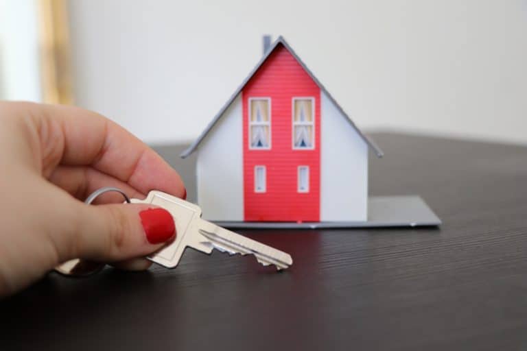 A person holding a key to a model house with further changes due to COVID-19 leasing laws.