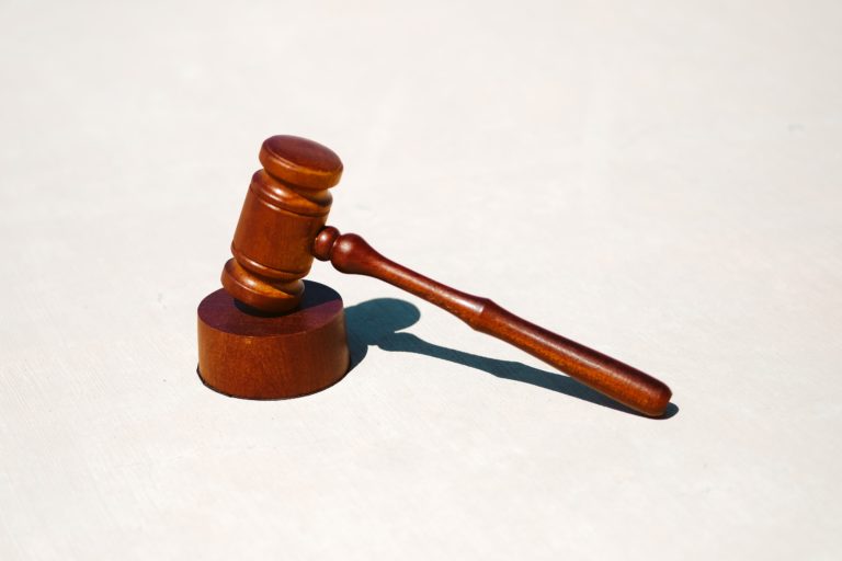 A wooden gavel on a white surface relating to stealing.